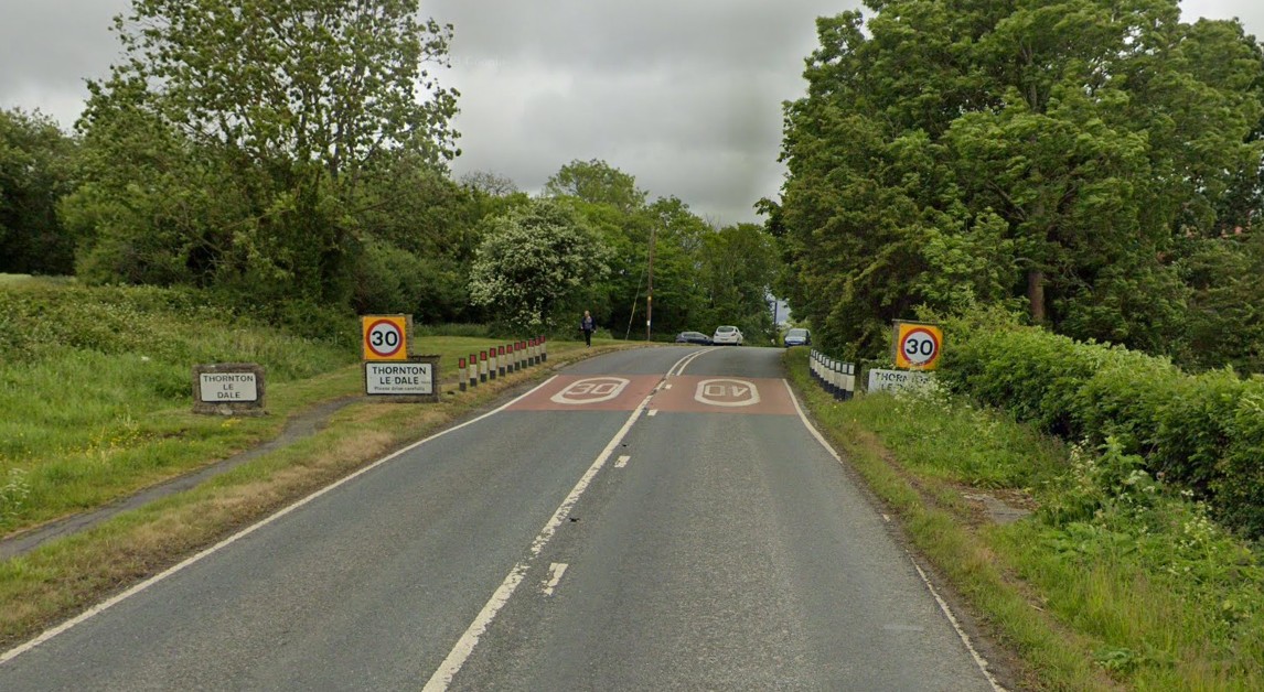 The A170 approaching Thornton-le-Dale with the village sign at the roadside