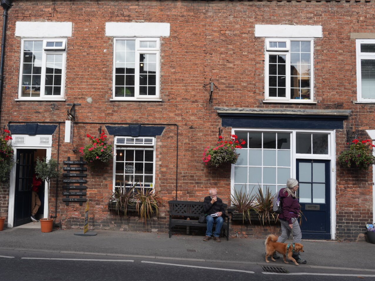 The Thornton Dale Fisheries frontage on Pickering Road, Thornton-le-Dale, with the fish and chip menu board beside the door and hanging baskets above the windows