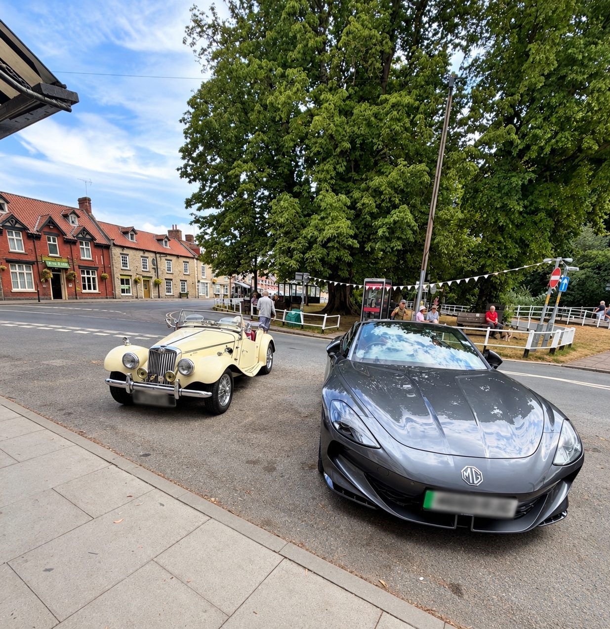 A cream MG TF and a modern grey MG sports car parked by the green
