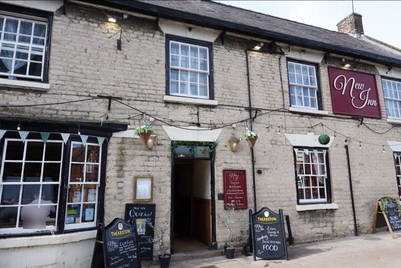 The stone front of the New Inn, with its sign and chalkboards