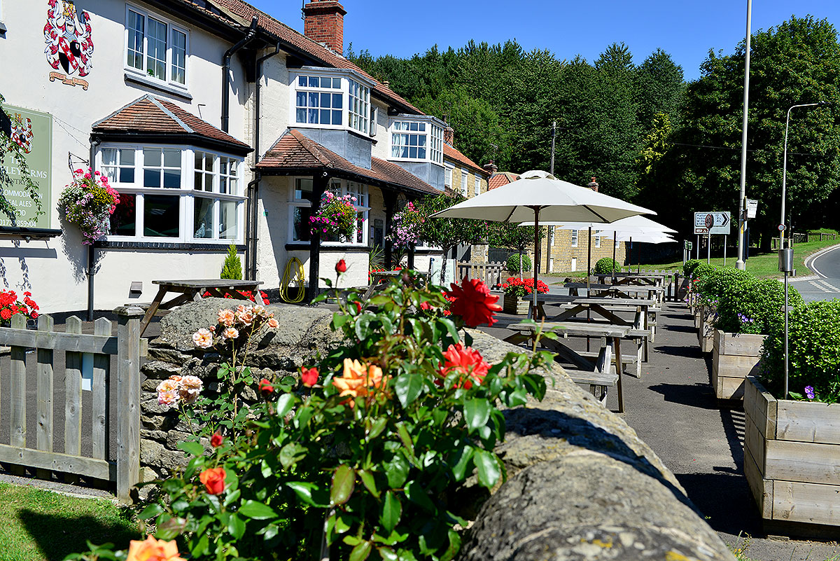 The Cayley Arms at Allerston, a white-painted country inn with roses, hanging baskets and picnic tables along the front