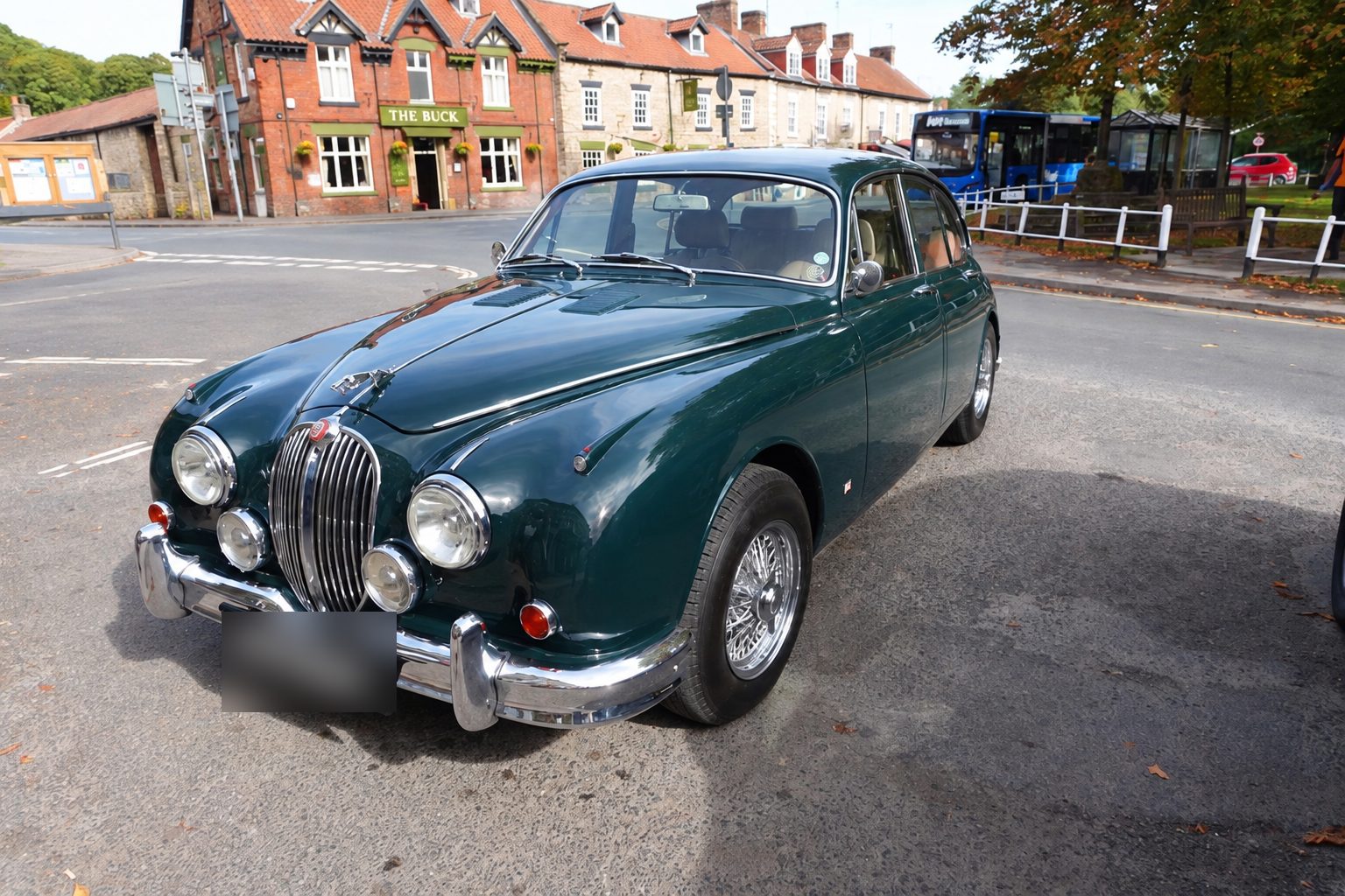 A green Jaguar Mk2 saloon parked in front of the Buck Inn