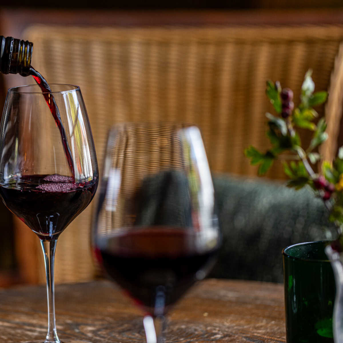Red wine being poured into a glass at a table inside The Buck