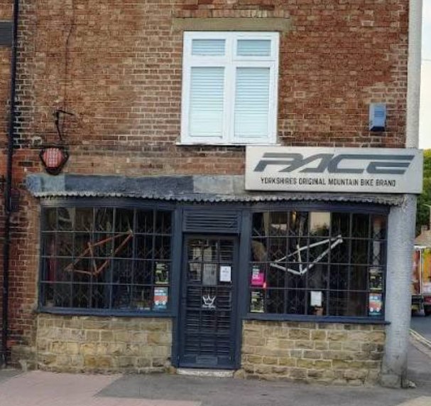 The Pace Cycles shopfront at 1 Pickering Road in Thornton-le-Dale: a brick building with a dark grey shopfront and a pale sign reading Pace, Yorkshires original mountain bike brand, with bicycle frames displayed in the windows