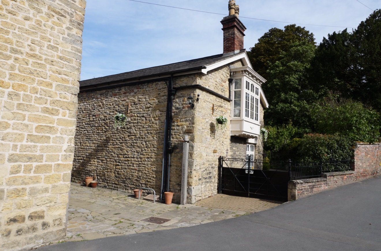 A stone house with an upstairs bay window and an iron gate