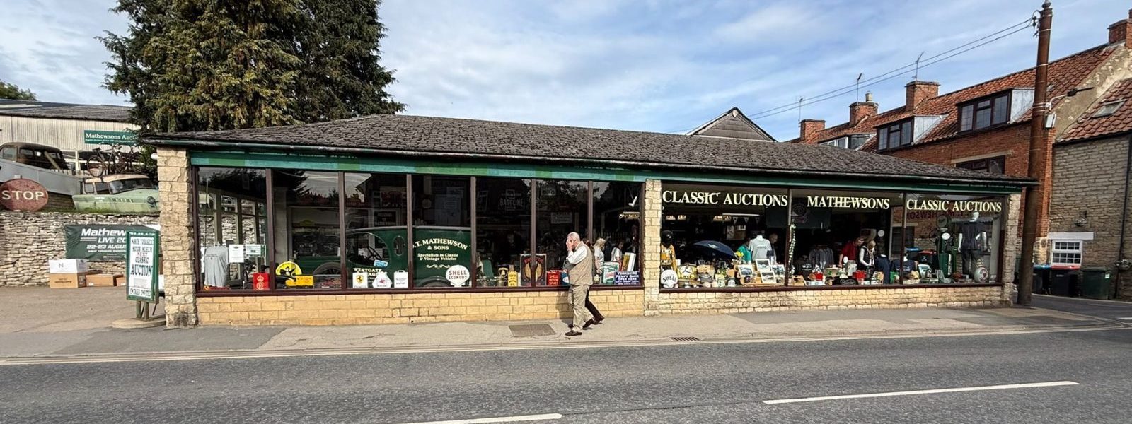 The long, low Mathewsons building on Pickering Road in Thornton-le-Dale seen from across the road, its green fascia reading Classic Auctions and Mathewsons above a run of shop windows