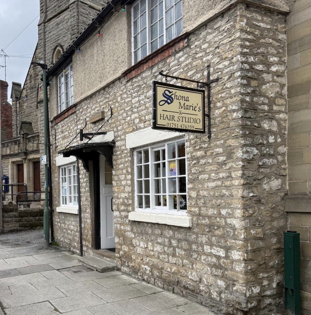 The stone frontage of Shona Marie's Hair Studio in Thornton-le-Dale, with a hanging sign showing the business name and telephone number