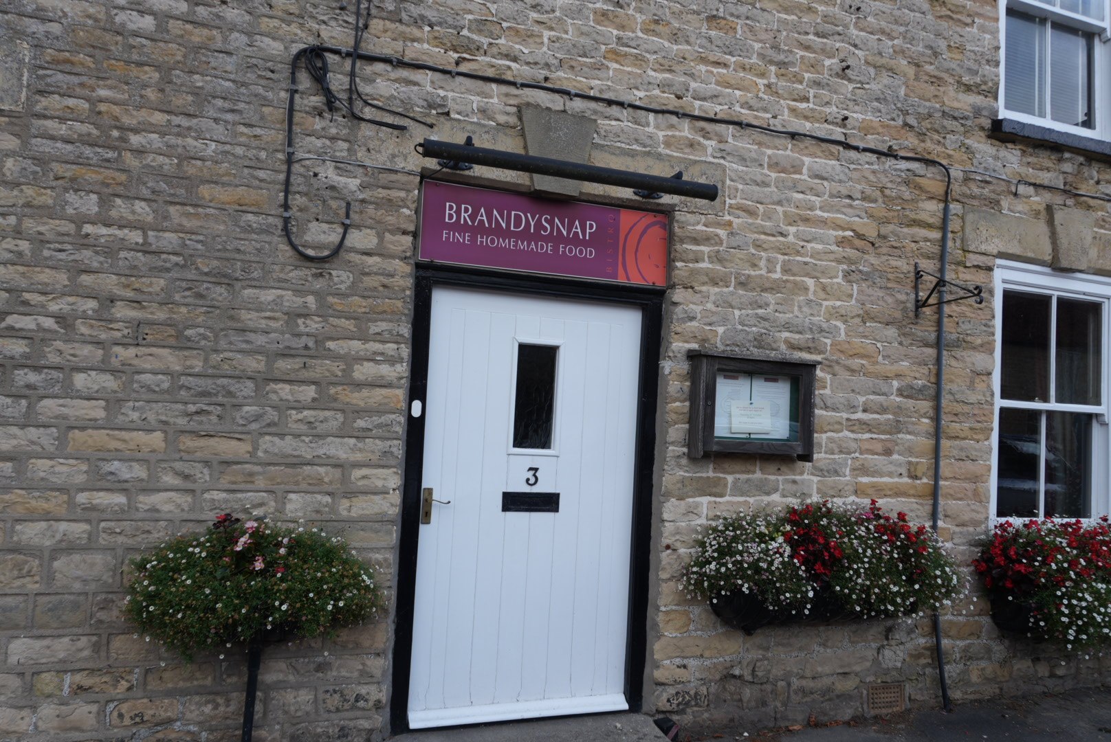 Brandysnap Bistro entrance on Whitbygate, Thornton-le-Dale, with a purple sign above the white door