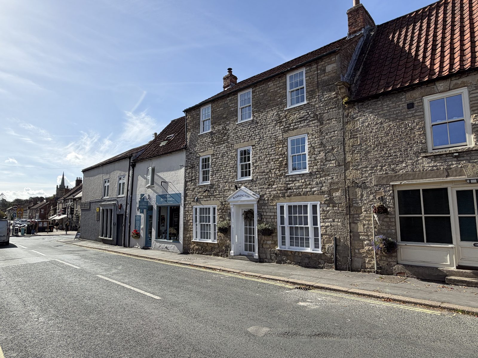 A brick and stone street with Warrington House on the right