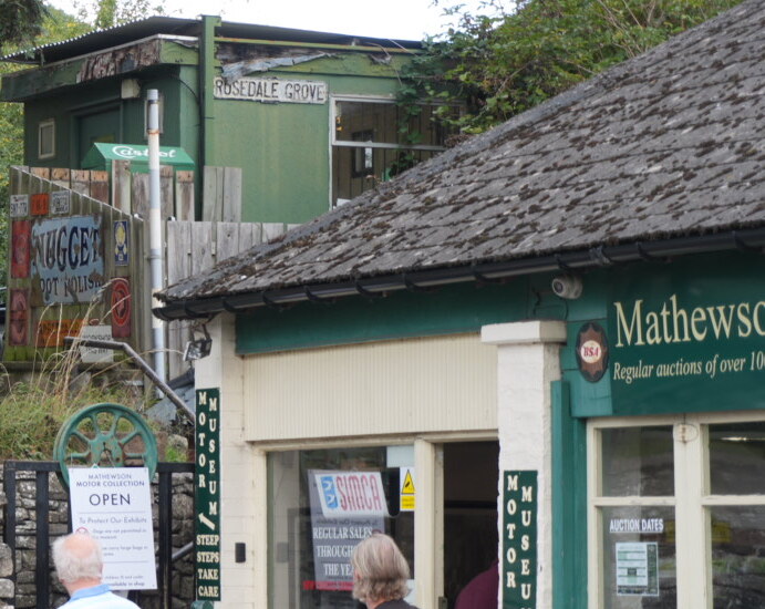 The entrance to the Mathewsons motor museum in Thornton-le-Dale, with green boards reading Motor Museum and a sign warning of steep steps