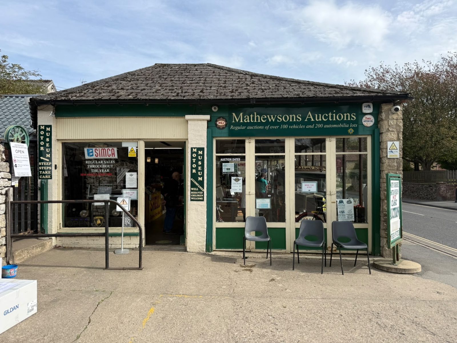 The Mathewsons Auctions office in Thornton-le-Dale, with a green fascia, notices in the windows and three grey chairs outside