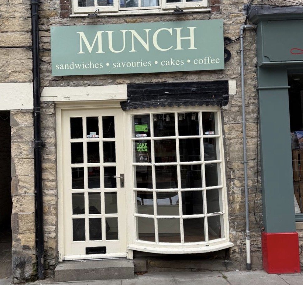 Munch cafe in Thornton-le-Dale, with a green sign listing sandwiches, savouries, cakes and coffee above the bay window and a takeaway sign in the window
