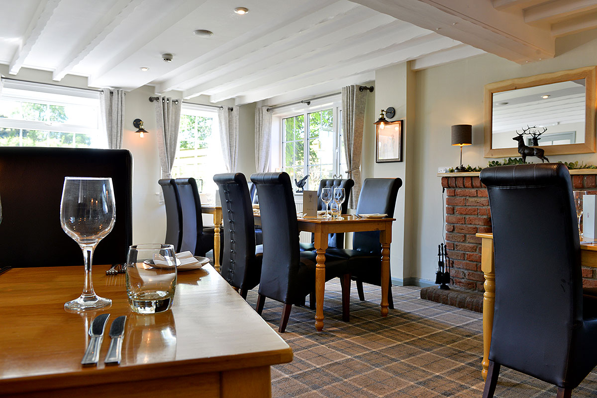The restaurant at the Cayley Arms, with laid tables, dark leather chairs and a brick fireplace