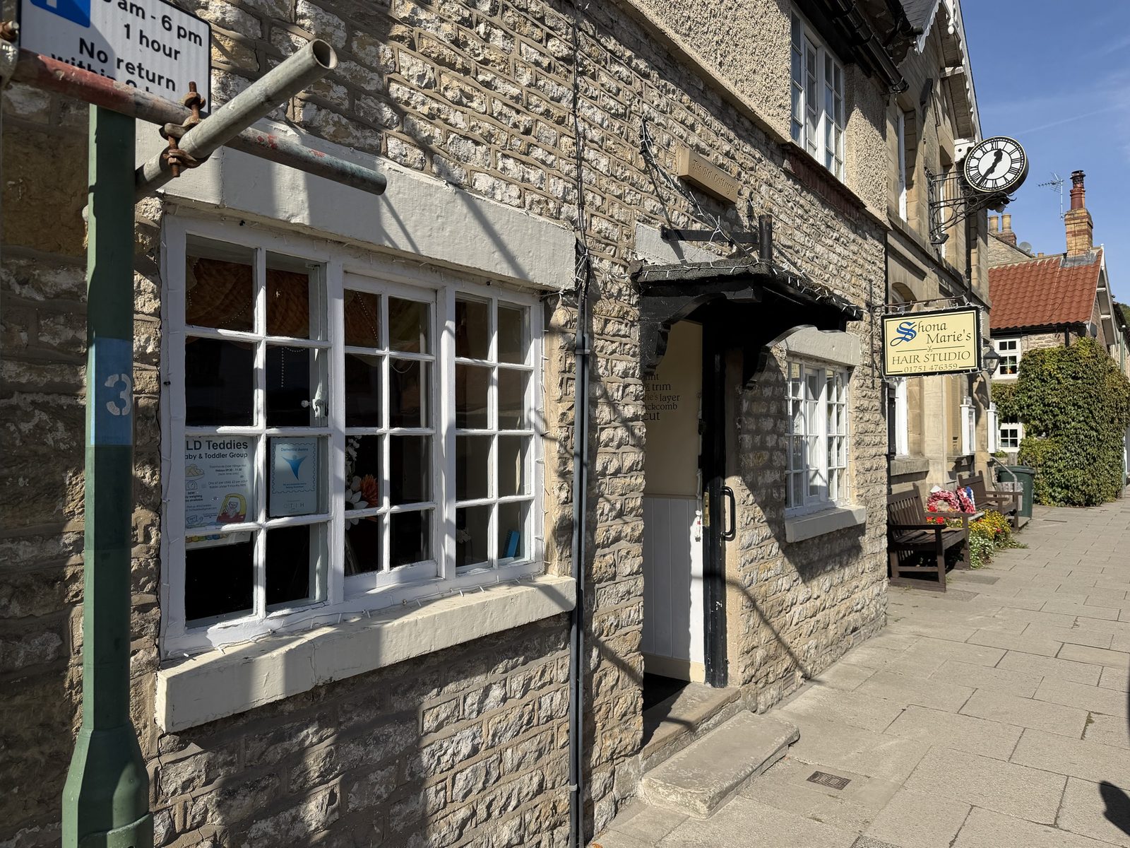 A stone shopfront and cottage on a paved street
