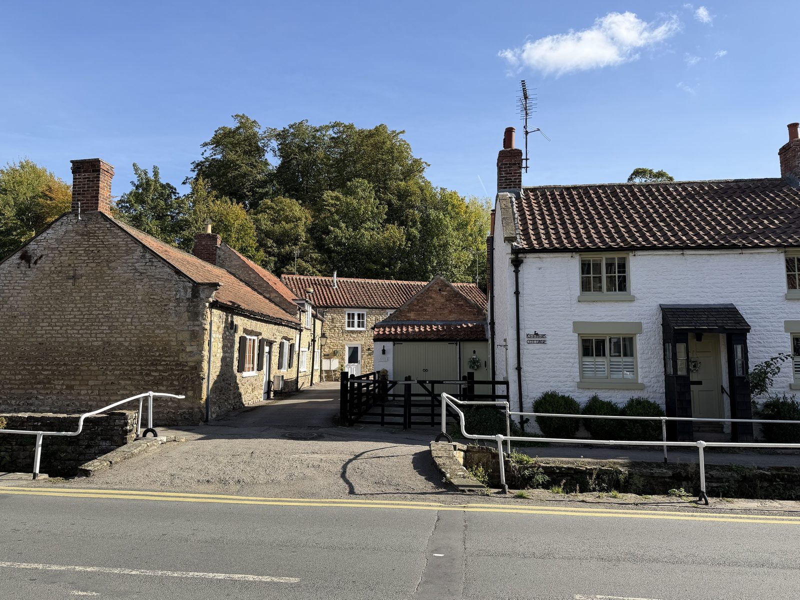Stone and whitewashed cottages beyond a low wall and railings beside the beck