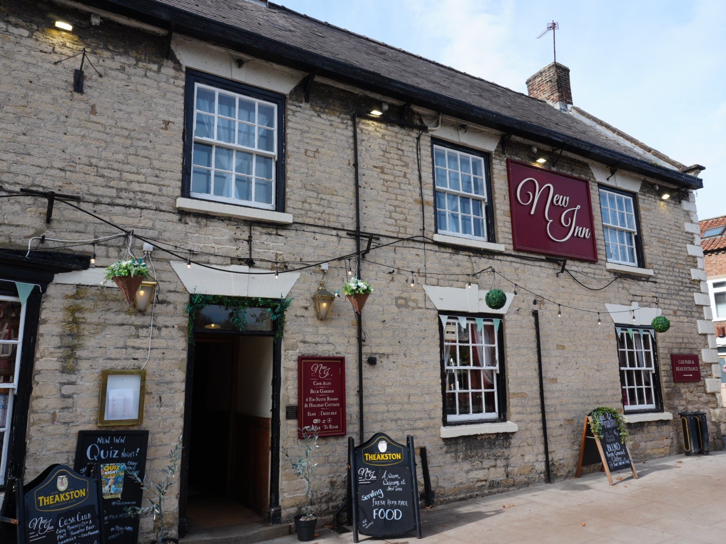 The stone frontage of The New Inn on Maltongate in Thornton-le-Dale, with its red sign and pavement A-boards